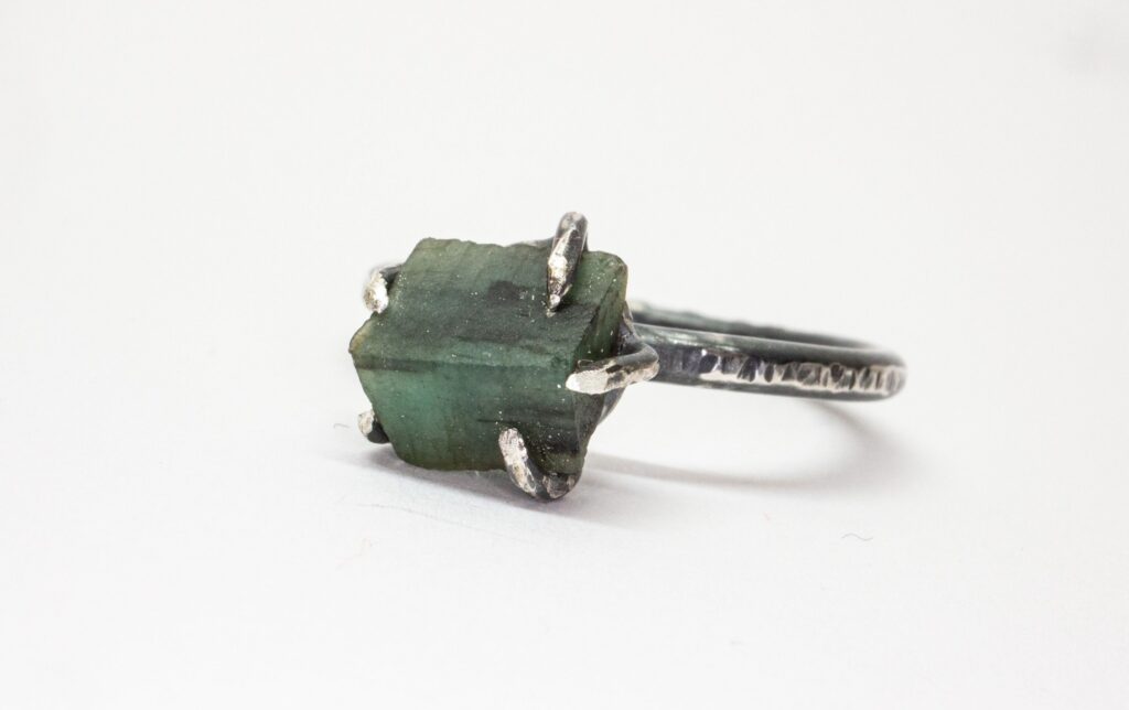 Kontakta Katrosi Jewelry -En bild på handgjord silverring med oslipad smaragd. Ringen är gjod av oxiderat sterling silver